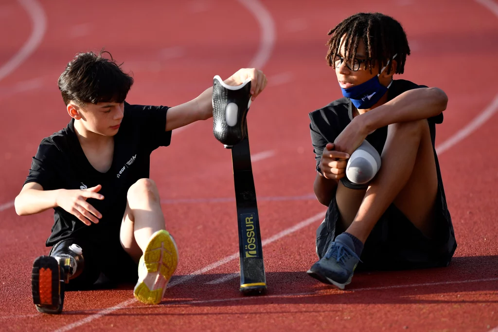 deux enfants handisport qui pratiquent de la course sur un terrain d'athlétisme